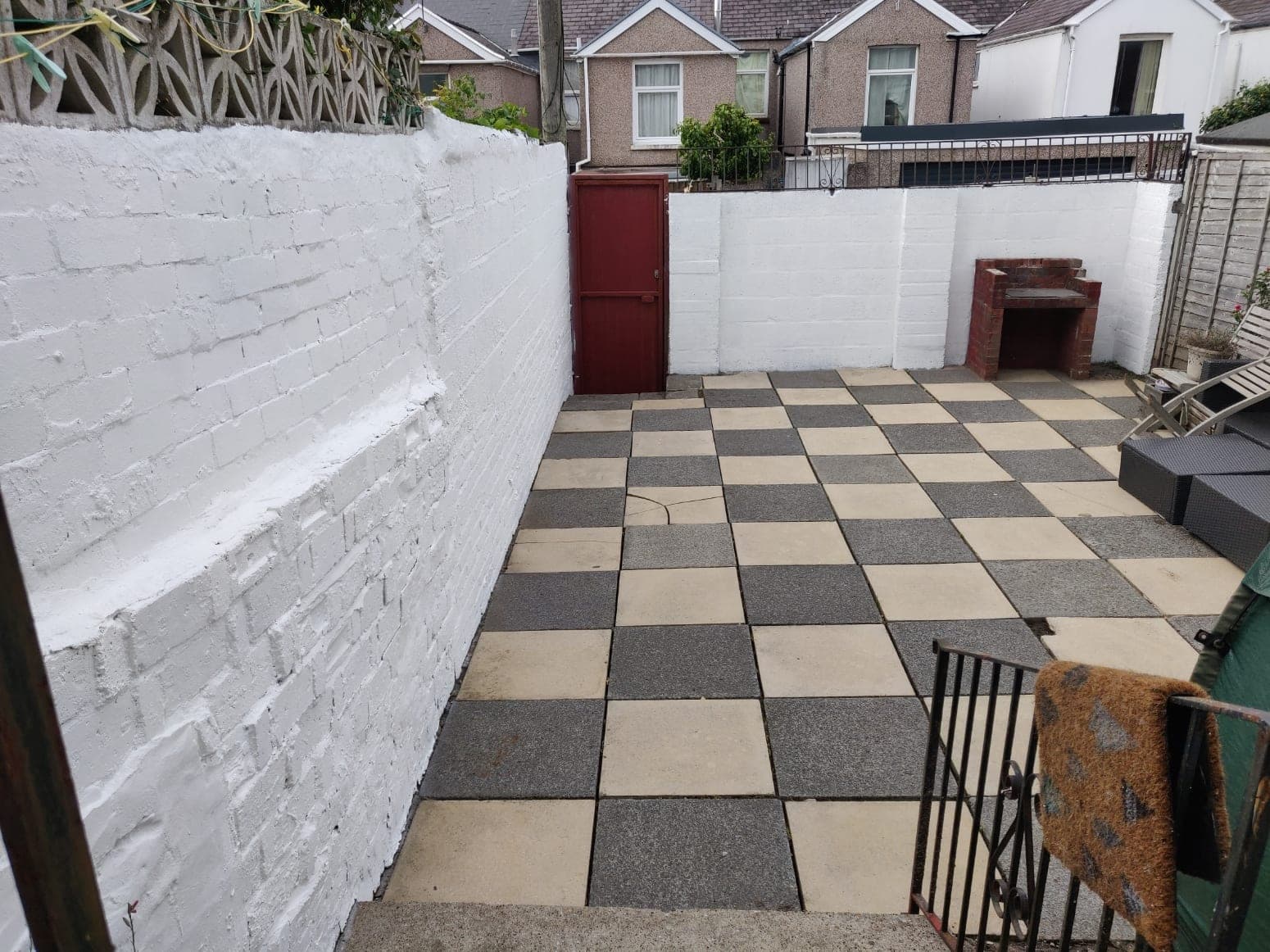 A courtyard with cleaned chequerboard paving and freshly painted white walls