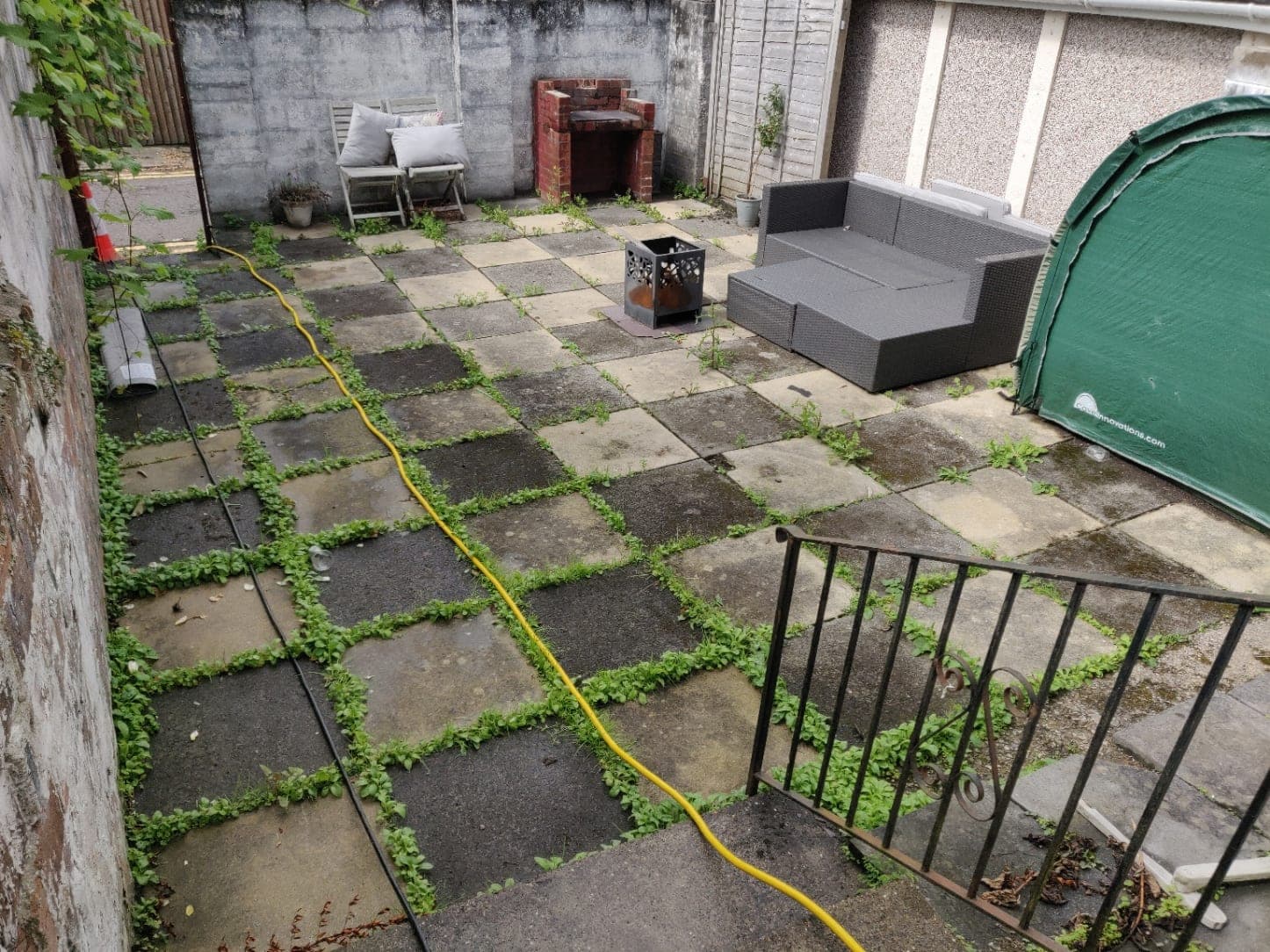 A courtyard with dirty paving and unpainted walls, before the booked job