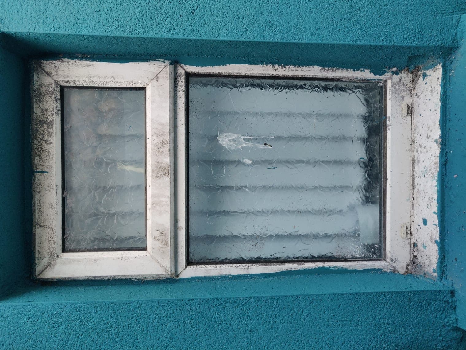 A rear window with rotten, dirt-blackened frames, photographed on site